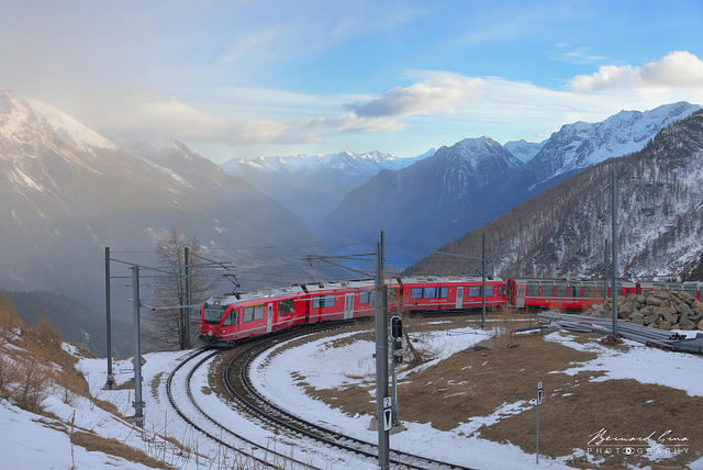 Courbe du train de la Rhtische Bahn au niveau de la gare de l’Alp Grm, altitude 2 091 m, au dessus du Valposchiavo et de son lac. Au fond, les Alpes Bergamaises captent les dernires lueurs   Bernard Grua